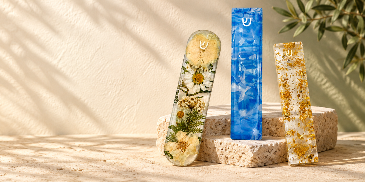 Floral, blue wedding-glass and gold-fleck mezuzah designs arranged on sunlit stone.